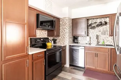 a kitchen with wooden cabinets and black appliances at King & Queen First Floor Unit! 1-2c Georgetown Villas in Fairview Park