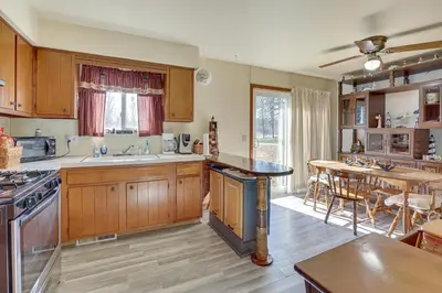 a large kitchen with wooden cabinets and a dining room at Family-Friendly Home with Fire Pit about 10 Mi to Akron! in Uniontown