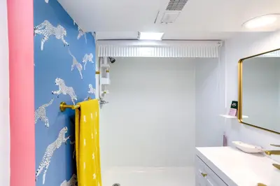 a bathroom with a shower with a yellow door at Gordon Square Studio about 4 Mi to Downtown Cleveland! in Cleveland