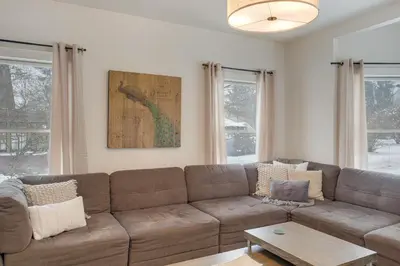 a living room with a brown couch and two windows at Peninsula Paradise - Walk to Hiking and Shopping! in Peninsula