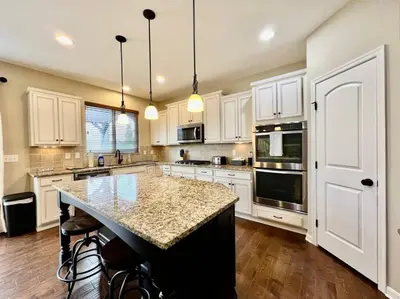 a kitchen with white cabinets and a granite counter top at Exclusive Golf Club Paradise in Lebanon