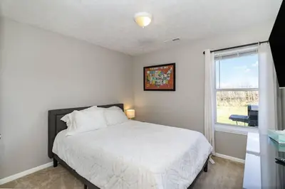 a bedroom with a white bed and a window at Relaxing home near Interstate in Monroe