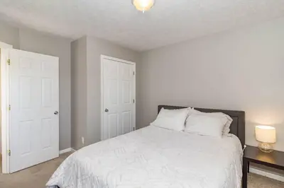 a bedroom with a white bed and two white doors at Relaxing home near Interstate in Monroe
