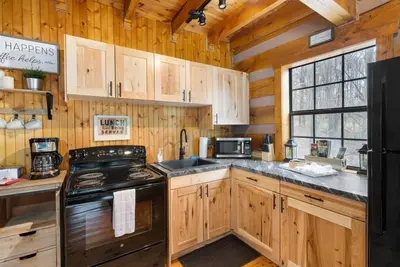 a kitchen with wooden cabinets and a black stove at Deerview Cabin by Wanderlust Properties in Logan