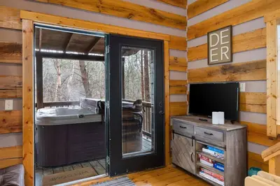 a living room with a sliding glass door and a tv at Deerview Cabin by Wanderlust Properties in Logan