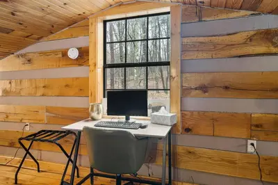 a desk with a computer in a room with wooden walls at Deerview Cabin by Wanderlust Properties in Logan