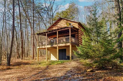 a log cabin in the woods with a balcony at Deerview Cabin by Wanderlust Properties in Logan