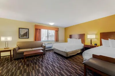 a hotel room with two beds and a couch at Best Western Falcon Plaza - Bowling Green in Bowling Green