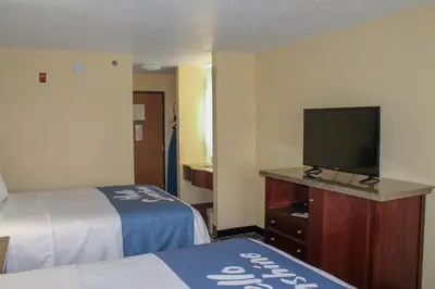a hotel room with two beds and a flat screen tv at Days Inn by Wyndham Batavia Ohio in Batavia