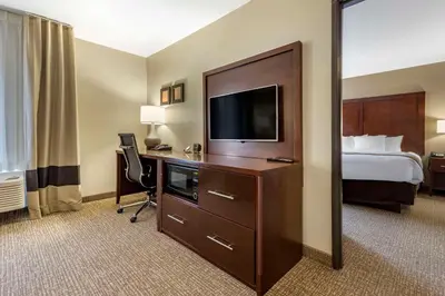 a hotel room with a bed and a desk with a television at Comfort Suites Bridgeport - Clarksburg in Bridgeport
