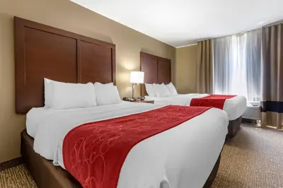 a hotel room with two large beds with red sheets at Comfort Suites Bridgeport - Clarksburg in Bridgeport