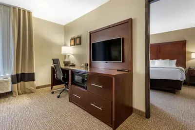a hotel room with a bed and a desk with a television at Comfort Suites Bridgeport - Clarksburg in Bridgeport