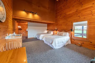 a bedroom with two beds and a clock on the wall at The Lodge at Fields of Home in Millersburg