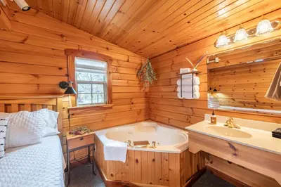 a log cabin bathroom with a tub and a sink at Olive Leaf Cabin in Millersburg