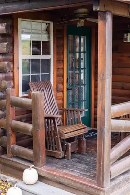 two rocking chairs on the porch of a log cabin at Olive Leaf Cabin in Millersburg