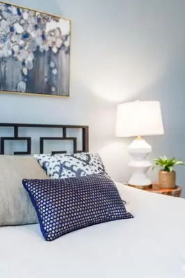 a white bed with a blue pillow and a lamp at Stylish Flat in Walkable Downtown w Parking in Cincinnati