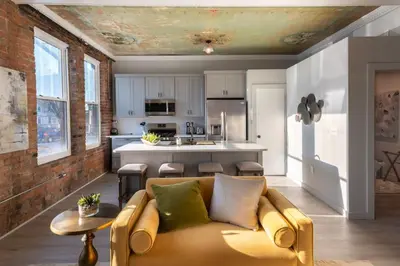 a living room with a couch and a kitchen at Parlor - Explore OTR and DT from Restored 1894 Italianate in Cincinnati