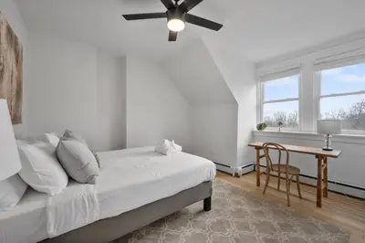 a bedroom with a bed with a ceiling fan and a table at Cozy 2.5BR near Zoo - Hospitals - UC - Free Parking in Cincinnati