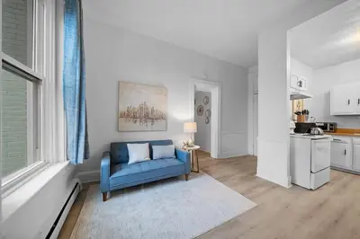 a living room with a blue couch and a kitchen at Cozy 1BR with Parking - Near UC, Zoo, Downtown in Cincinnati