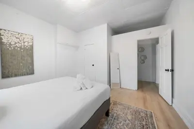 a white bedroom with a white bed and a rug at Cozy 1BR with Parking - Near UC, Zoo, Downtown in Cincinnati
