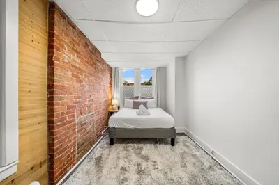 a bedroom with a bed and a brick wall at Cozy Studio with Parking - Near UC, Zoo, Downtown in Cincinnati
