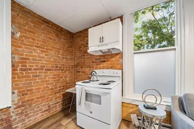 a kitchen with a white stove and a brick wall at Cozy Studio with Parking - Near UC, Zoo, Downtown in Cincinnati