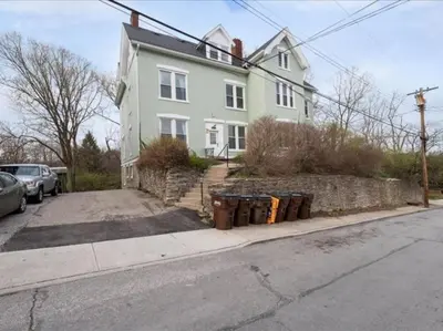 a white house with a bunch of trash cans on a street at Cozy Studio with Parking - Near UC, Zoo, Downtown in Cincinnati