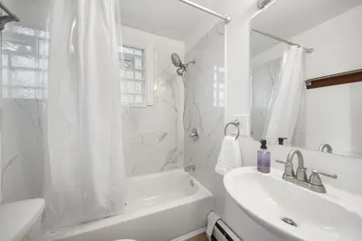 a white bathroom with a tub and a sink and a shower at Cozy Studio with Parking - Near UC, Zoo, Downtown in Cincinnati