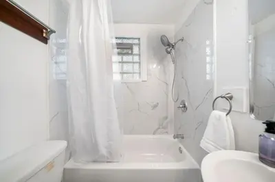 a white bathroom with a tub and a sink at Cozy Studio with Parking - Near UC, Zoo, Downtown in Cincinnati