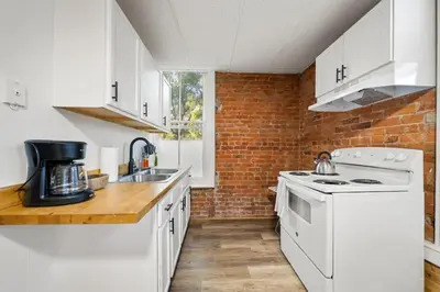 a kitchen with white appliances and a brick wall at Cozy Studio with Parking - Near UC, Zoo, Downtown in Cincinnati
