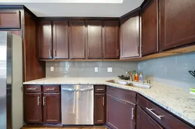a kitchen with wooden cabinets and a stainless steel dishwasher at Classy 2BR Condo Near City Centre - OTR, UC, Zoo in Cincinnati