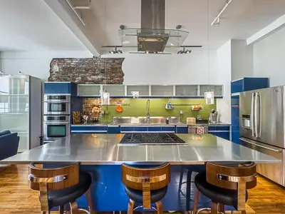 a large kitchen with blue and green cabinets at The Historic Lyric Penthouse with Private Rooftop in Cincinnati