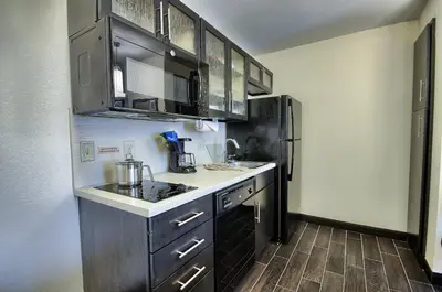 a kitchen with black cabinets and a refrigerator at Candlewood Suites Columbus - Grove City by IHG in Grove City