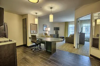 a living room with a table and a kitchen at Candlewood Suites Columbus - Grove City by IHG in Grove City