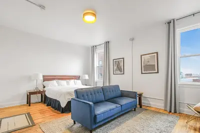 a bedroom with a bed and a blue chair at Library Square Suites in Toledo