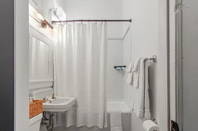 a white bathroom with a shower curtain and a sink at Library Square Suites in Toledo