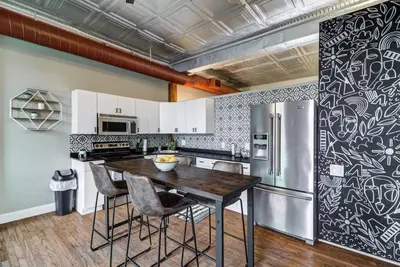 a kitchen with a wooden table and a refrigerator at Good Vibes Loft - DT CLE Walk To All The Stadiums in Cleveland