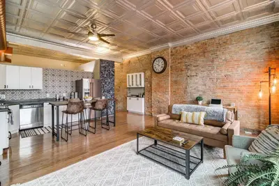 a living room with a couch and a brick wall at Good Vibes Loft - DT CLE Walk To All The Stadiums in Cleveland