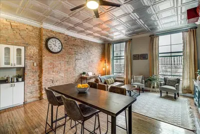 a living room with a table and a clock on the wall at Good Vibes Loft - DT CLE Walk To All The Stadiums in Cleveland