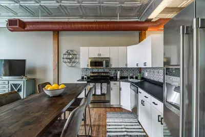 a kitchen with white cabinets and a wooden counter top at Good Vibes Loft - DT CLE Walk To All The Stadiums in Cleveland