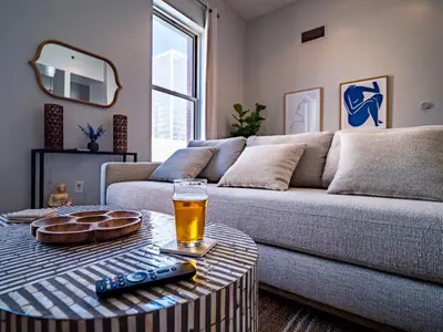 a living room with a couch and a glass of beer on a table at Skyloft Condo - Walk To Stadiums - City Views in Cleveland