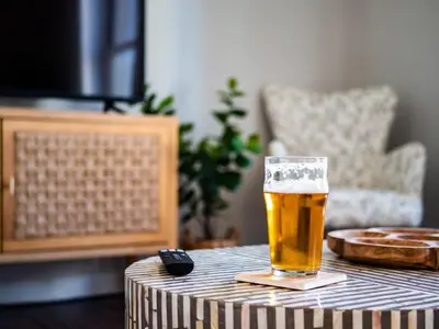 a glass of beer on a table with a remote control at Skyloft Condo - Walk To Stadiums - City Views in Cleveland