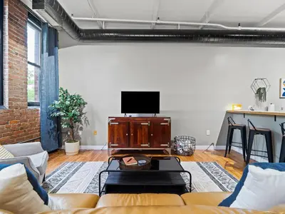 a living room with a couch and a flat screen tv at Lakefront Loft - Downtown - Shuffle Board Table in Cleveland
