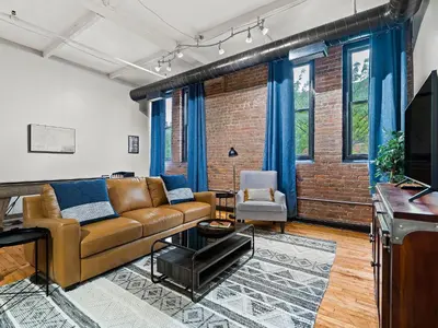 a living room with a couch and a television at Lakefront Loft - Downtown - Shuffle Board Table in Cleveland