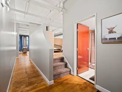an open hallway with stairs and a painting of a cow on the wall at Lakefront Loft - Downtown - Shuffle Board Table in Cleveland
