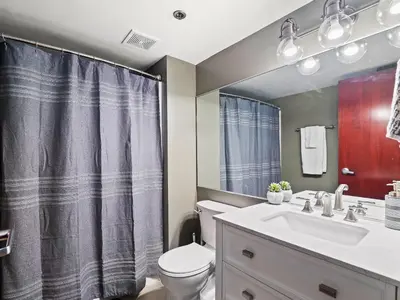 a bathroom with a sink and a toilet and a mirror at Lakefront Loft - Downtown - Shuffle Board Table in Cleveland