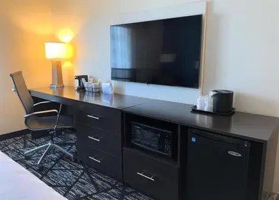 a hotel room with a desk with a flat screen tv at SureStay by Best Western Cambridge in Cambridge