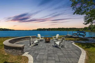 a patio with a table and chairs and a lake at Landmark Lakehouse - luxury living in PLX in Akron
