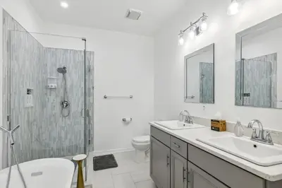 a white bathroom with two sinks and a shower at Landmark Lakehouse - luxury living in PLX in Akron