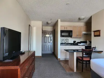 a living room with a television and a kitchen at Ashley Quarters Hotel Airport-Cincinnati in Florence